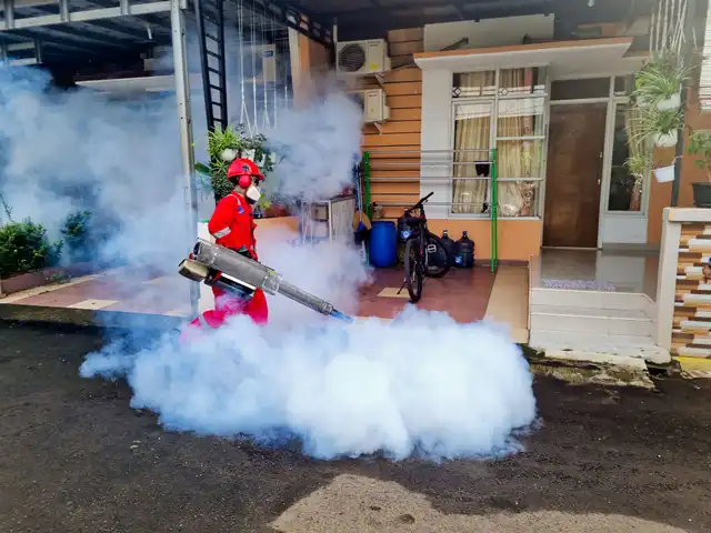A pest control technician fogging outside a house