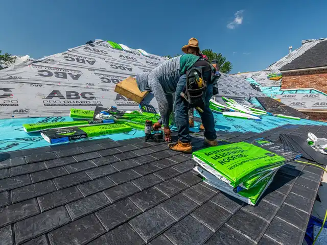 A roofer laying underlayment on a new roof