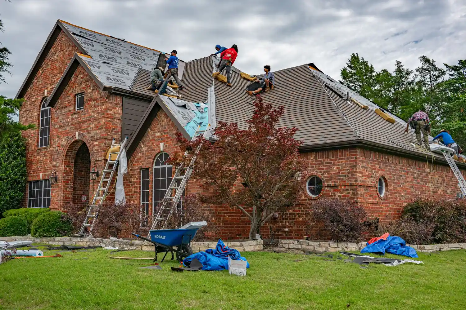 Roofers replacing shingles on a brick house